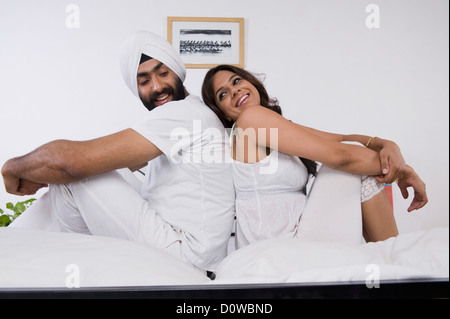 Sikh paar sitzen Rücken an Rücken auf dem Bett Stockfoto