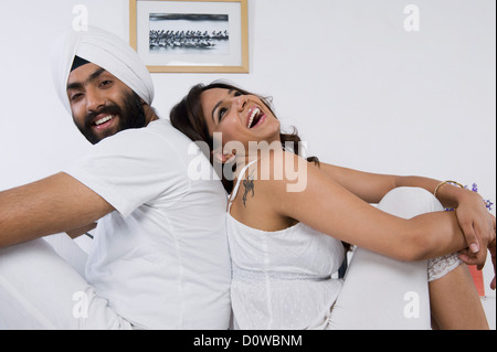 Sikh paar sitzen Rücken an Rücken auf dem Bett Stockfoto