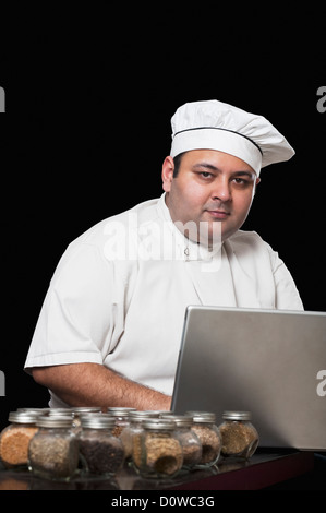 Koch mit einem Laptop und verschiedene Gewürze Stockfoto