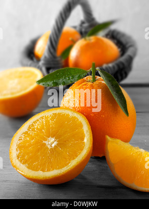 Frische Orangen ganze und geschnittene Hälften mit Blättern