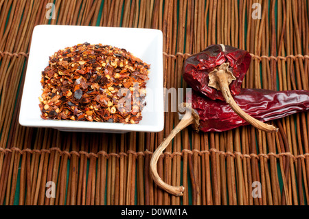 Grob gemahlener roter Pfeffer und ganze getrocknete Paprika. Stockfoto