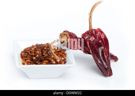 Grob gemahlener roter Pfeffer und ganze getrocknete Paprika. Weiß isoliert Stockfoto