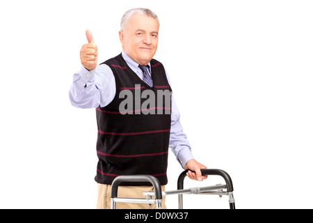 Ein reifer Herr isoliert mit einer Gehhilfe und einen Daumen aufgeben auf weißem Hintergrund Stockfoto