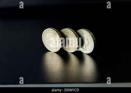 Pfund Sterling Münze drei Münzen glänzend werfen Schatten auf reflektierende schwarze Oberfläche auf Tisch Schreibtisch für Banken und Finanzdienstleistungen Stockfoto