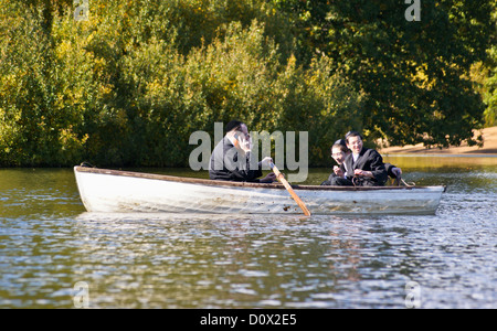 Orthodoxen jüdischen Mann mit einem Mobiltelefon in einem Ruderboot, hohlen Teiche, Leytonstone, London, England Stockfoto