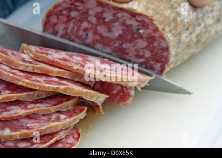 große Scheiben leckere Salami Slice mit dem Stahl Messer Stockfoto
