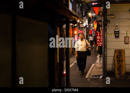 Nach der Arbeit geht ein japanische Gehalt Mann durch eine Gasse in Shinjuku, auf der Suche nach einem Ort für ein Abendessen Stockfoto