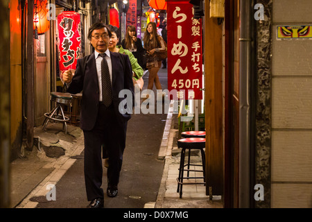 Nach der Arbeit geht ein japanische Gehalt Mann durch eine Gasse in Shinjuku, auf der Suche nach einem Ort zu Abend essen Stockfoto