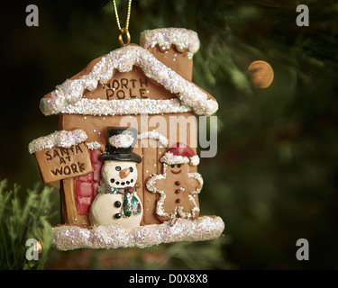 Ein Weihnachtsbaum Ornament Darstellung Frosty, der Schneemann und ein Lebkuchenmann vor einem Lebkuchen die Werkstatt des Weihnachtsmanns. Stockfoto