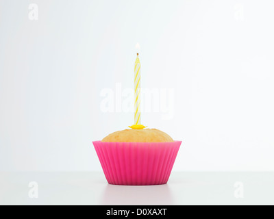 Nahaufnahme von einzelnen Cupcake in rosa Silikonform mit Kerze an der Spitze Stockfoto