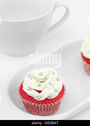 roten Muffin mit weißen Creme und Silber Candy auf Porzellanteller gelegt Stockfoto