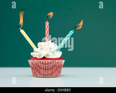 Muffins auf dem Tisch mit drei Kerzen auf blauem Hintergrund geblasen Stockfoto