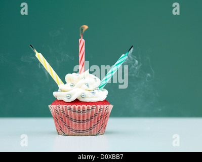 Muffins auf dem Tisch mit drei Kerzen auf blauem Hintergrund geblasen Stockfoto