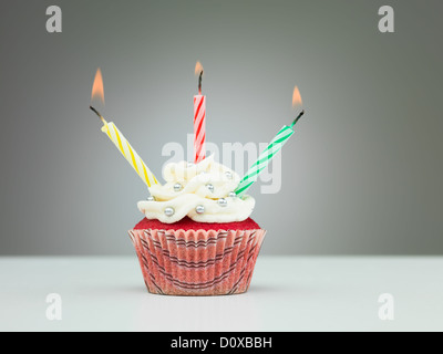 Muffins auf dem Tisch mit drei Kerzen auf neutralem Hintergrund mit Farbverlauf Stockfoto