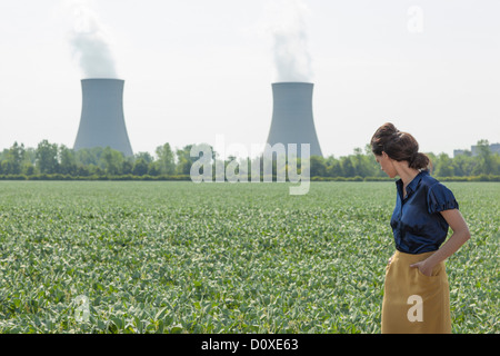 Frau in Soja-Bohne reichte Blick hinter zum Kernkraftwerk Stockfoto