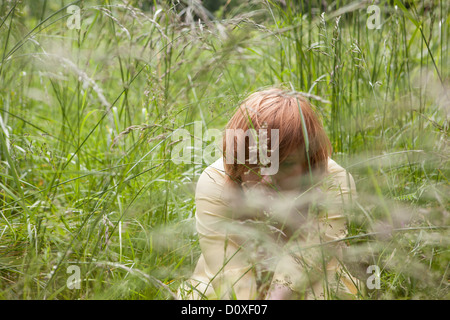 Junge Frau versteckt in Rasen Stockfoto