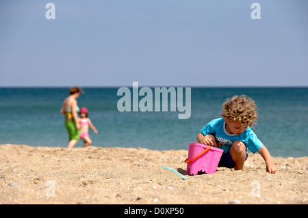 Boy am Strand mit Eimer und Spaten Stockfoto