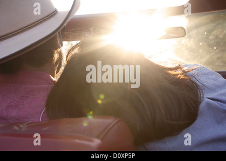 Kopf auf Freundes Schulter ruht, wie er im Sonnenlicht fährt Frau Stockfoto