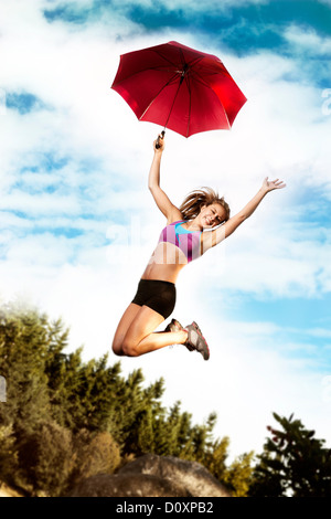 Teenager-Mädchen mit Regenschirm springen Stockfoto