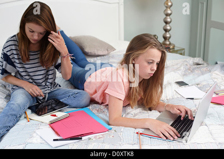 Mädchen im Teenageralter mit Laptop und digital-Tablette auf Bett Stockfoto