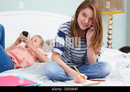 Teenager-Mädchen sitzt auf dem Bett, mit Handy Stockfoto