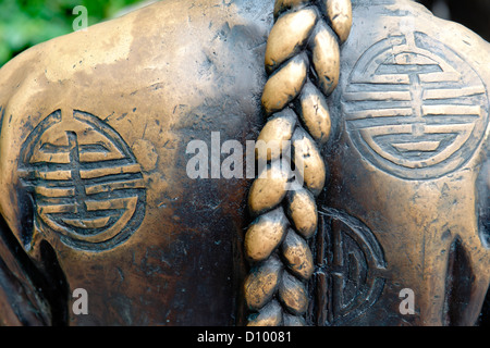 Nahaufnahme des chinesischen Symbolen und eng geflochtenes Haar auf die Bronzeskulptur "The River Kaufleute" durch den Singapore River. Stockfoto