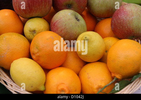 rote Äpfel, Orangen und Zitronen in einem Korb zum Verkauf auf den Markt Stockfoto