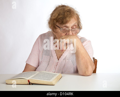 alte Frau in Gläsern liest das Buch Stockfoto