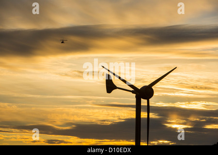 Ein Ultraleichtflugzeug fliegt vorbei an einer Windkraftanlage auf Kirkstone Pass, Lake District, Cumbria, UK bei Sonnenuntergang. Stockfoto