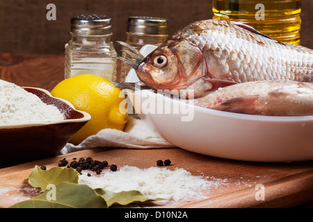 Frische Karpfen auf einem Küchentisch mit Zitrone und Mehl Stockfoto