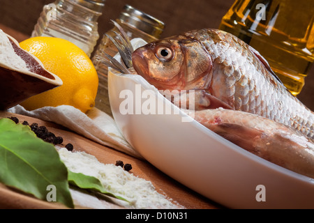 Frische Karpfen auf einem Küchentisch mit Zitrone und Mehl Stockfoto