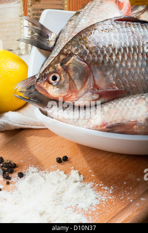 Frische Karpfen auf einem Küchentisch mit Zitrone und Mehl Stockfoto