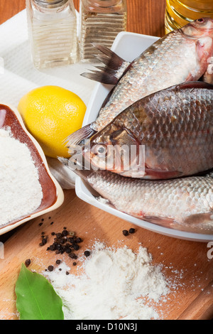 Frische Karpfen auf einem Küchentisch mit Zitrone und Mehl Stockfoto