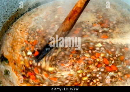 Bohnensuppe mit Gemüse, traditionell zubereitet, in eine große Schüssel geben und mit einem Holzlöffel gemischt. Stockfoto