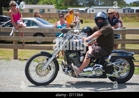 Ein Mann und ein junges Kind ein Harley Davidson Motorrad. Motorräder in Mangawhai, Northland, Nordinsel, Neuseeland. Stockfoto