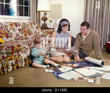 1970ER JAHREN BAUPLÄNE FAMILIE MUTTER VATER TOCHTER LESUNG PLÄNE FÜR NEUE HEIMAT Stockfoto