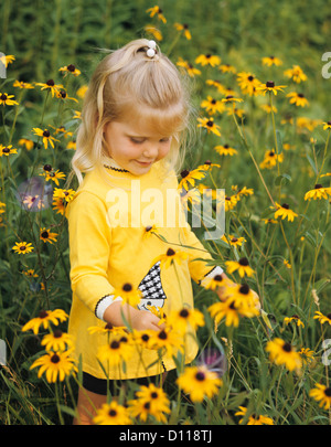 1970ER JAHREN BLONDE MÄDCHEN MIT GELBEN KLEID IM BEREICH DER BLUMEN BLACK EYED SUSANS Stockfoto