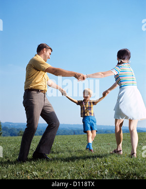 1970ER JAHRE FAMILIE MUTTER VATER BOY SPIELEN RING UM ROSEN, HAND IN HAND Stockfoto