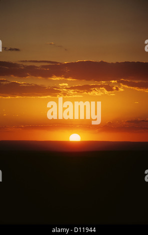 GELBE SONNENEINSTELLUNG AM DUNKLEN HIMMEL MIT WOLKEN IM GOLDENEN HIMMEL Stockfoto