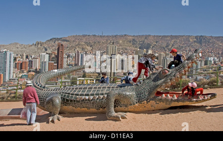 Kinder spielen am Spielplatz mit Blick auf Stadt Cbd, Krokodil-Statue Wolkenkratzer von La Paz, Bolivien Stockfoto