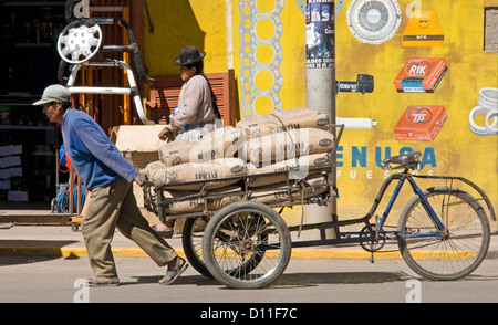 Man zieht Fahrrad Wagen beladen mit Taschen von Zement entlang einer Straße in der Stadt Puno, Peru Südamerika Stockfoto