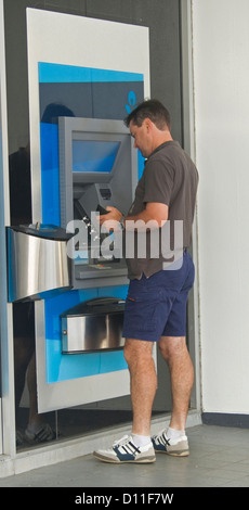 Mann in Freizeitkleidung mit Bankautomat - ATM - vor einer bank Stockfoto