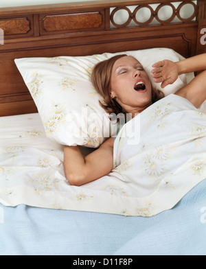 1970ER JAHREN FRAU IM BETT ZU GÄHNEN Stockfoto