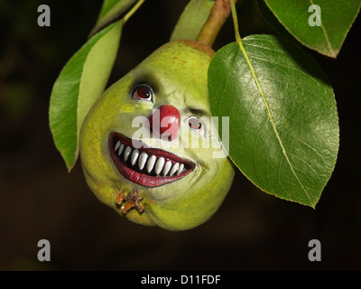 Humorvolle Bild der Birne mit glücklich, lächelndes Gesicht und leuchtenden Augen wachsen am Baum mit grünen Blättern und dunklem Hintergrund Stockfoto