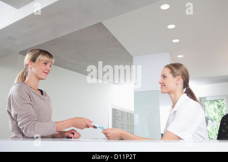 Deutschland, Patienten geben Versicherungskarte an Rezeption in Zahnarztpraxis Stockfoto