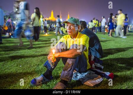 5. Dezember 2012 - Bangkok, Thailand - ein Mann sitzt allein auf dem Feld am Sanam Luang nach der öffentlichen Zeremonie zur Feier des Geburtstages von Bhumibol Adulyadej, der König von Thailand, am Sanam Luang, einem riesigen öffentlichen Raum vor dem Grand Palace in Bangkok Mittwoch Abend. Der König feierte seinen 85. Geburtstag Mittwoch und Hunderttausende von Thais besucht die lange Feier rund um den Grand Palace und das Royal Plaza, nördlich der Palast. Die thailändische Monarch wird von den meisten Thais als vereinigende Kraft in der thailändischen Gesellschaft, die noch nicht von der politischen Gewalt 2010 erholt verehrt. Stockfoto