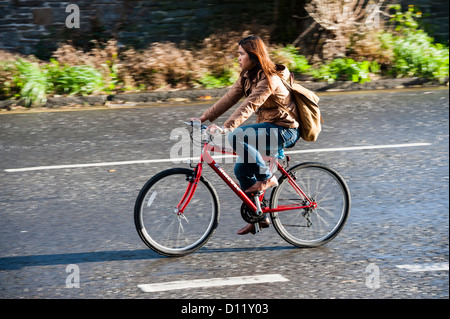 Ein junge Frau Radfahrer nicht tragen eine Sicherheit Helm Radfahren Radfahren radeln ein rotes Fahrrad UK Stockfoto