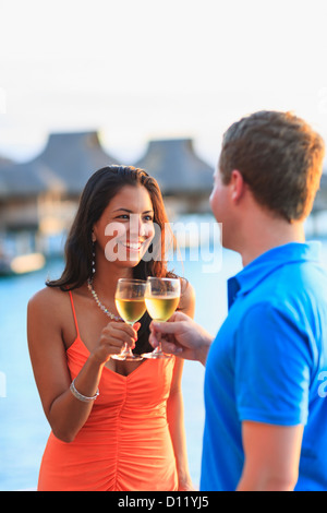 Mann und Frau bei einem Drink an der Wasserkante im Bora Bora Nui Resort And Spa Toasten; Gesellschaftsinseln, Südpazifik Stockfoto