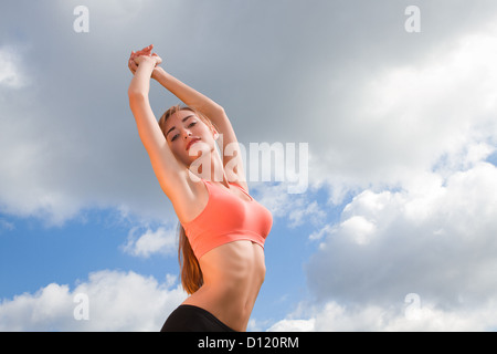 lächelnde sportliche Frau auf der Himmelshintergrund mit Händen Stockfoto