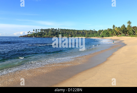 Ein einsamer Mann am frühen Morgen Angeln auf einem schönen weißen Sandstrand in Tangalle auf der Südküste Sri Lankas Stockfoto